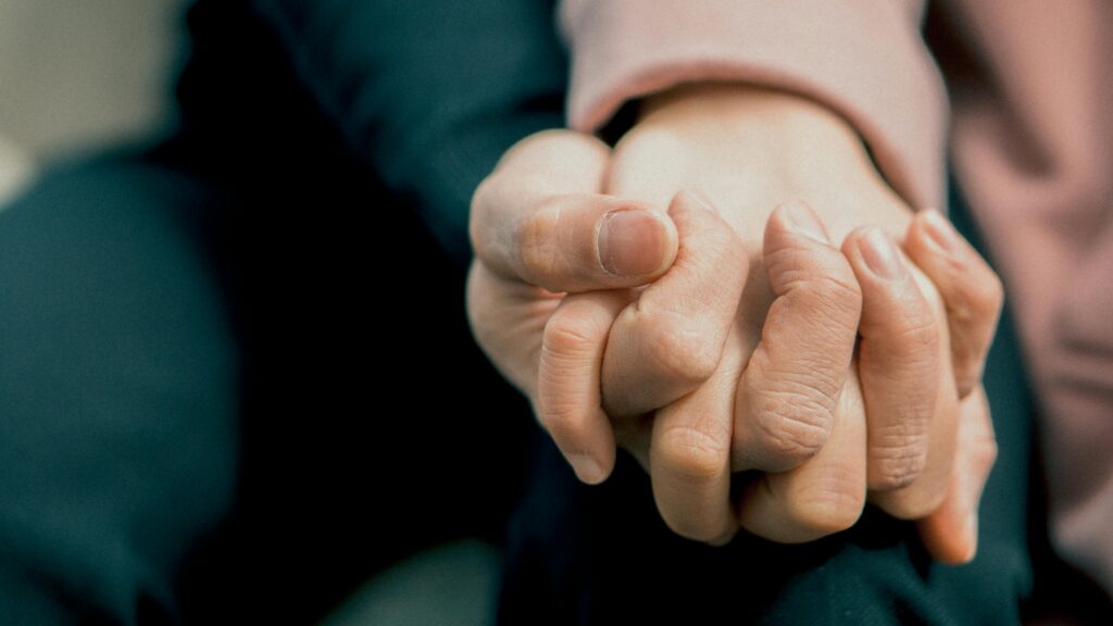 Close up shot of two individuals holding hands.