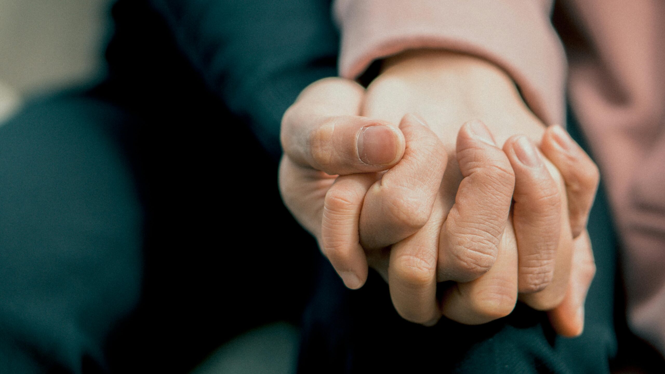 Close up shot of two individuals holding hands.